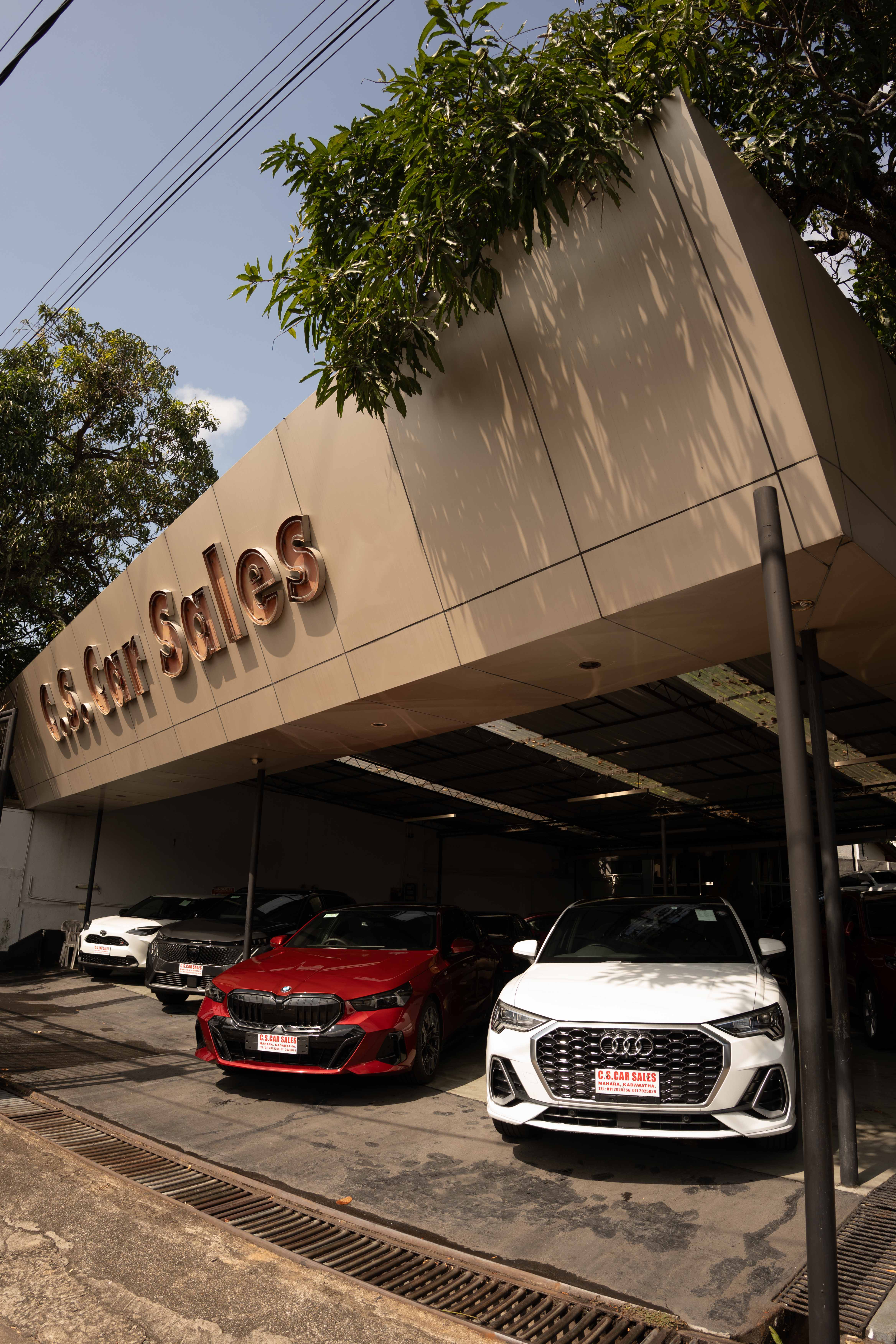 C.S. Car Sales showroom frontage with a red BMW and a white Audi on display